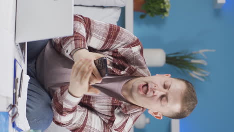 Vertical-video-of-Home-office-worker-man-having-problems-and-stress-on-the-phone.